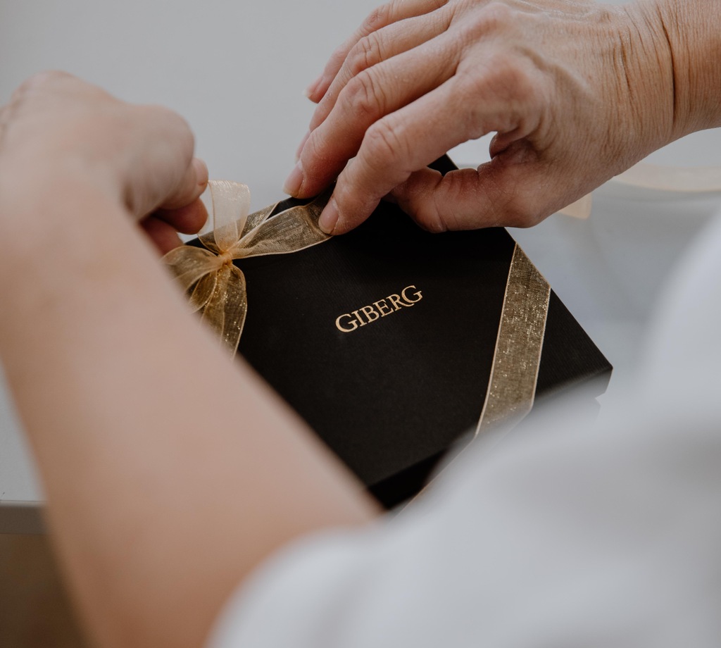 Firmengeschenke vom Schloss-Beck Hände verpacken eine elegante schwarze Geschenkbox als Firmengeschenk vom Schloss-Beck.
